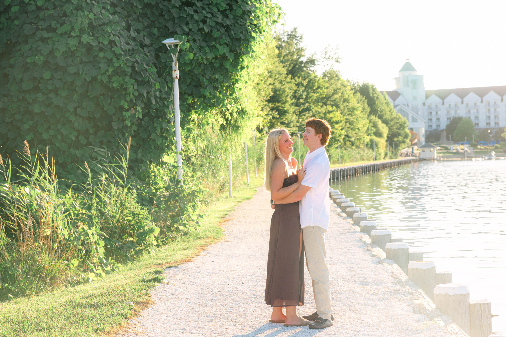 Samantha and Colin holding each other on a waterfront path at golden hour